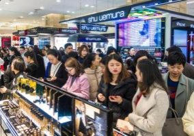 W75W8B Crowds of Chinese customers shop for cosmetics and skincare products at a shopping mall offering large discount due to the anniversary before the day